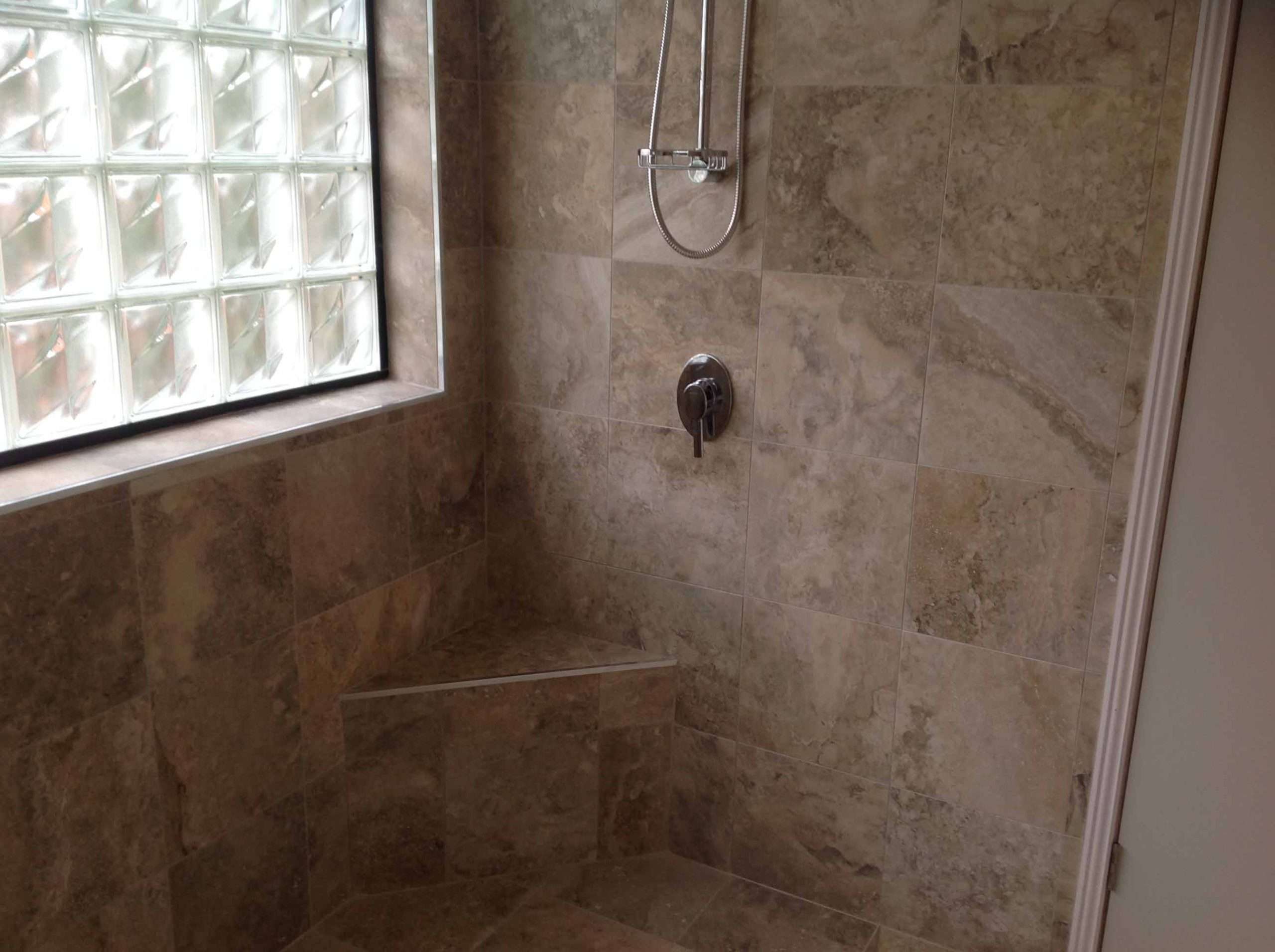 Tiled shower with a corner seat, glass block window and rail shower