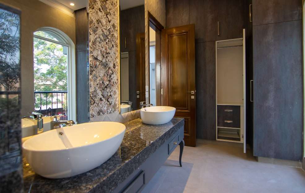 local Bathroom Renovations service Quakers Hill Granite vanity with two vessel basins beside a stone feature column and timber doors